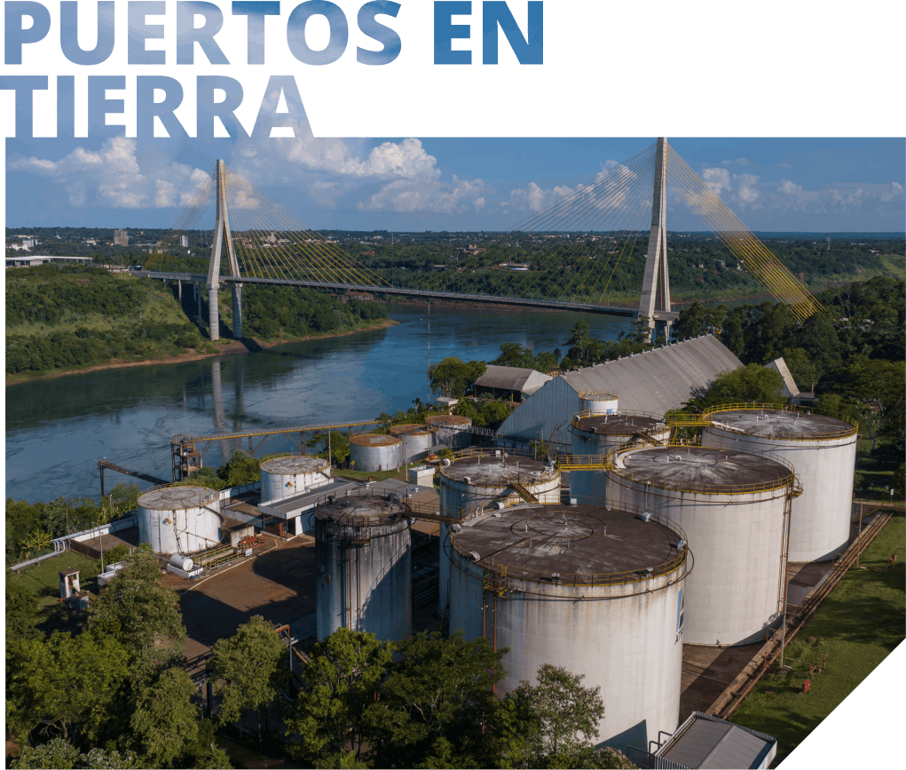 Tanques de almacenamiento de petróleo en tierra, con puente y río al fondo.